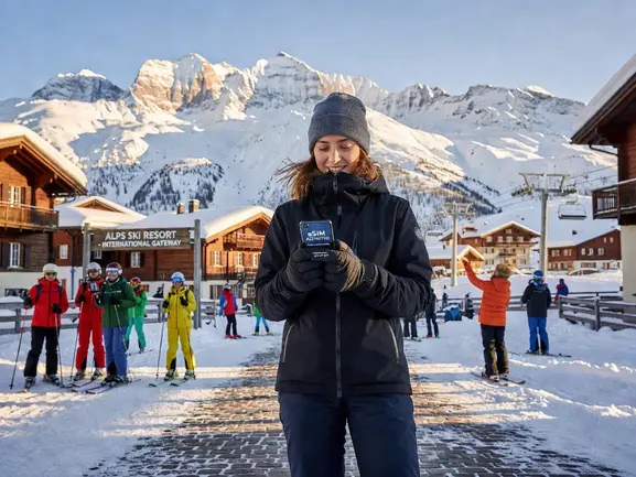 Skier on Alps slopes checking phone with eSIM connectivity - eSIMYat travel eSIM guide